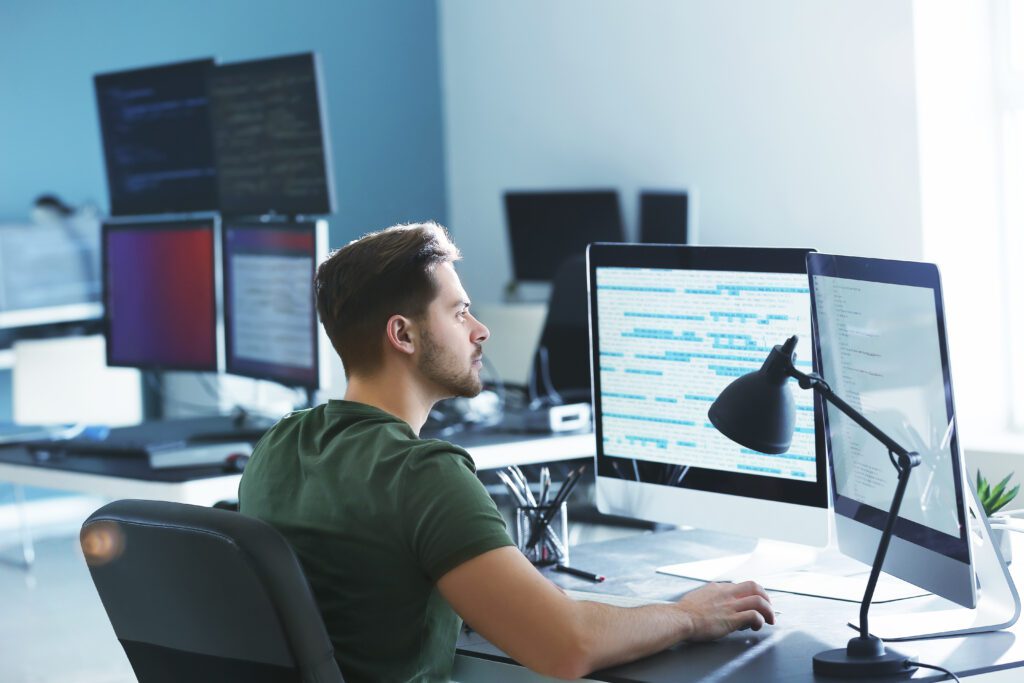 Stock photo of a professional working at a dual-monitor setup, symbolizing AWS cloud architecture and real-time infrastructure monitoring.
